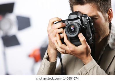 Young man taking photo with professional digital camera, focus on hand and lens - Powered by Shutterstock