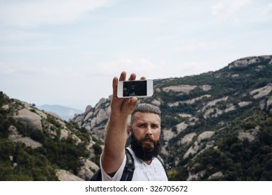 Young Man Taking Photo With Smart Phone At Mountain Road