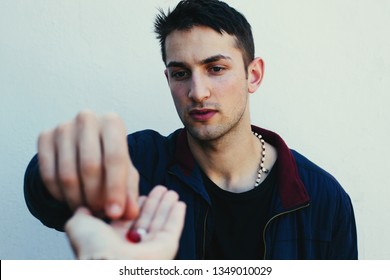 Young Man Taking Red Pill In Capsule From Doctor Hand