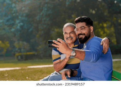 Young man taking selfie with his father at park - Powered by Shutterstock