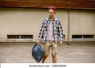 Young Man Taking A Trash Bag With Garbage Away