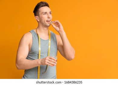 Young Man Taking Weight Loss Pills On Color Background