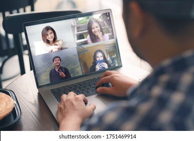 Young man talking about freelancer report in video conference. Asian team using laptop and tablet online meeting in video call.Working from coffee shop , Working remotely and Social isolation. - Shutterstock ID 1751469914