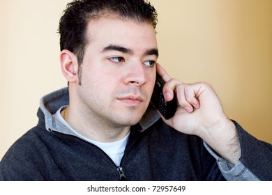 A Young Man Talking On His Cell Phone.  He Is Holding The Phone With His Right Hand But Listening With His Left Ear.