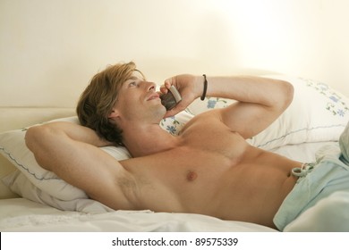 Young Man Talking On His Cell Phone, Laying Down On Bed.