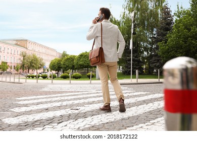 Young Man Talking On Phone While Crossing Street, Back View. Traffic Rules And Regulations