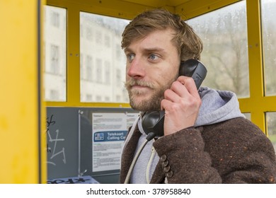 Young Man Talking On The Phone In A Phone Booth 