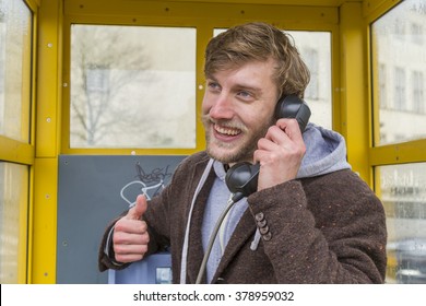 Young Man Talking On The Phone In A Phone Booth 