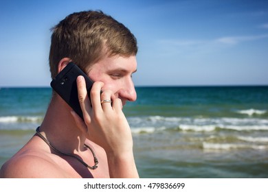 Young Man Talking On The Phone On The Sea Shore