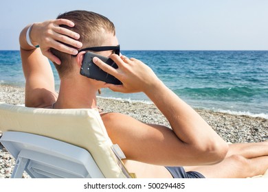 Young Man Talking On The Phone On The Beach