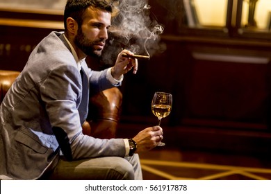 Young Man Tasting White Wine And Smoking Cigar