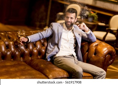 Young Man Tasting White Wine And Smoking Cigar