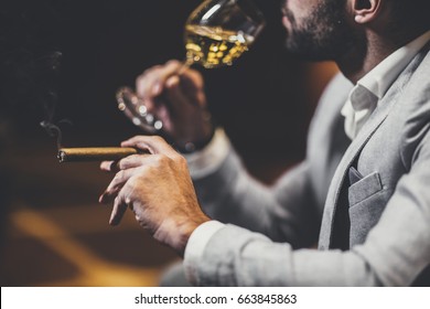 Young Man Tasting White Wine And Smoking Cigar