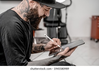 Young Man Tattoo Artist With Beard Holding Pencil And Sketch Looking Positive And Happy Standing And Smiling In Workshop Place