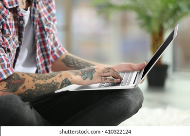 Young Man With Tattoo Using Laptop On A Floor At Home