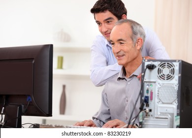 Young Man Teaching An Elderly Man Computer Skills