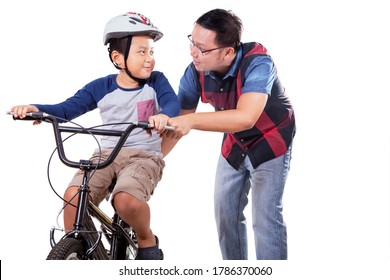 Young Man Teaching His Boy To Ride Bike For The First Time With Happy Expression In The Studio. Isolated On White Background