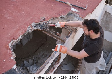 Young Man Tearing The Roof Of A House Down Using A Mallet.