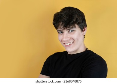 A Young Man, A Teenager Smiling With Big Eyes As If Mocking, Laughing At Someone, On Orange Background, The Guy Has A Beautiful Face And A Little Evil With Elements Of Bullying Smile, Copy Space