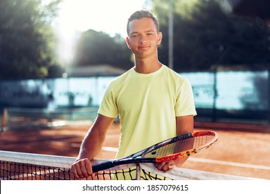 Young Man Teenager With Tennis Racket Standing Near Net On Clay Court