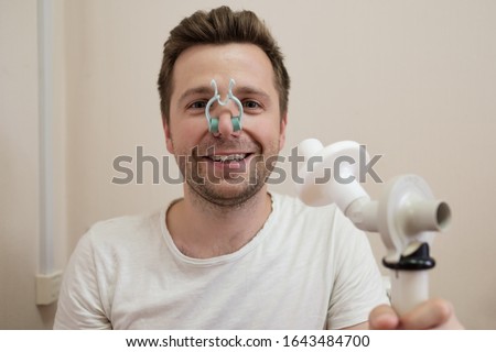 Young man testing breathing function by spirometry having health problem.