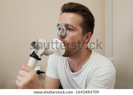 Young man testing breathing function by spirometry having health problem.