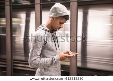 A young man texts while waiting for a NYC subway train. Shot during the Autumn of 2016