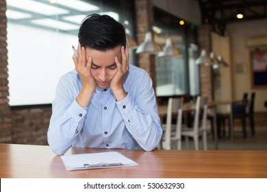 Young Man Thinking Hard On Task At Cafe Table