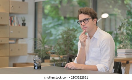 Young Man Thinking while Sitting in Office