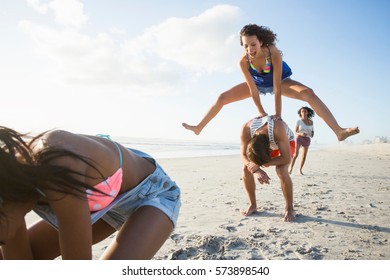 Young Man And Three Female Friends Playing Leapfrog On Beach, Cape Town, South Africa