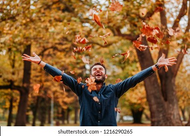 Young Man Throwing Autumn Leaves In The Air