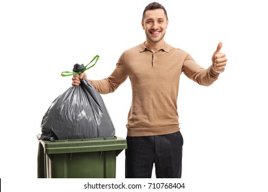 Young man throwing out the trash and making a thumb up gesture isolated on white background