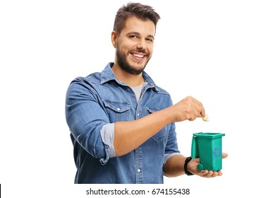 Young Man Throwing A Piece Of Garbage In A Small Recycling Bin Isolated On White Background