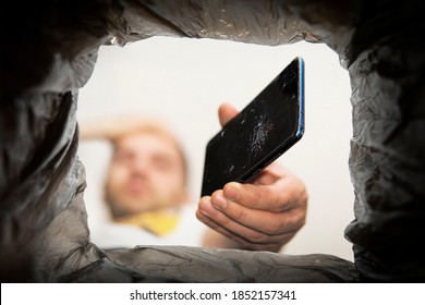 Young Man Throwing Smartphone In Litter Bin Outdoors. Recycling A Broken Smartphone.