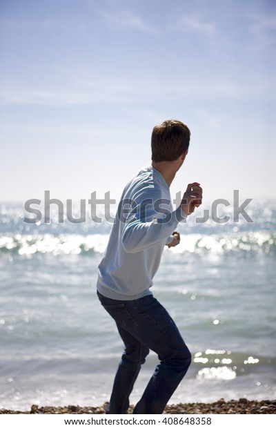 A young man throwing\
stones in the sea