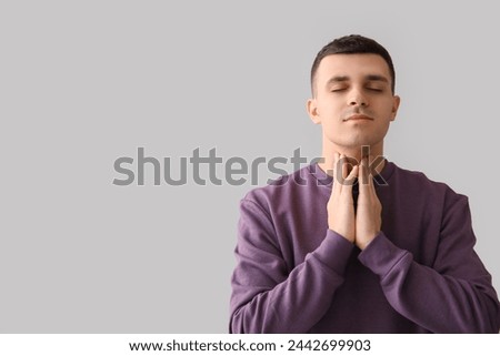 Young man with thyroid gland problem on light background