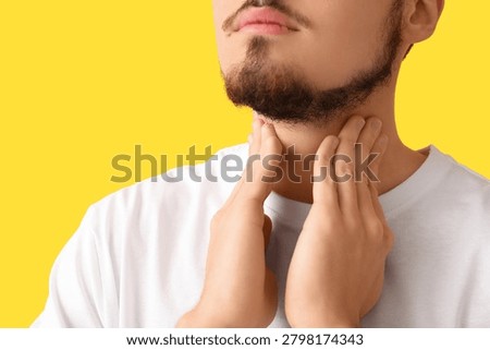 Young man with thyroid gland problem on yellow background, closeup