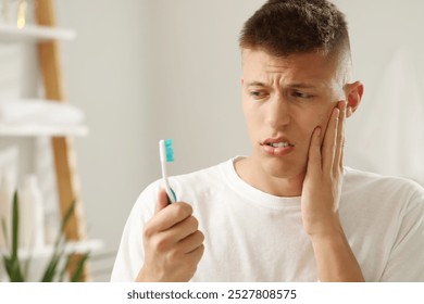 Young man with toothbrush suffering from toothache in bathroom - Powered by Shutterstock