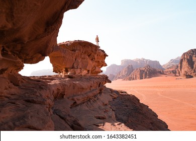 Young man is to the top of cliff. Wadi Rum also known as The Valley of the Moon is a valley cut into the sandstone and granite rock in southern Jordan to the east of Aqaba.