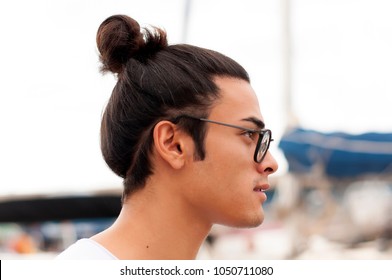 Young Man With The Top Knot And Glasses In The Sea Port