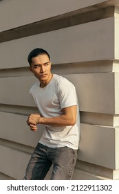 Young Man With Top Knot Lean Back Against The Wall Under The Sunset