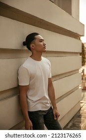 Young Man With Top Knot Lean Back Against The Wall Under The Sunset