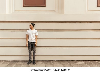 Young Man With Top Knot Lean Back Against The Wall Under The Sunset