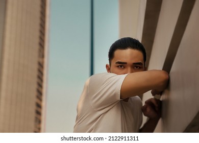 Young Man With Top Knot Leaning Against The Wall Under The Sunset