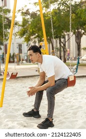 Young Man With Top Knot Sitting In The Park Under The Sunset