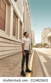 Young Man With Top Knot Standing In The City Under The Sunset