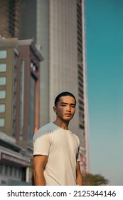 Young Man With Top Knot Standing In The City Under The Sunset