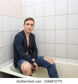 A Young Man In Torn Jeans Is Sitting In The Bathtub