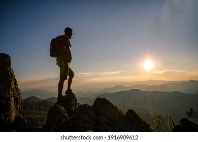 Young man tourist with backpack relaxing on top rock and enjoying sunset