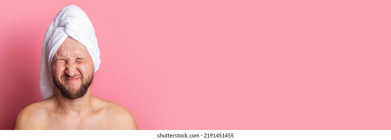 Young Man With A Towel Over His Head With His Eyes Shut Tightly Closed Eyes On A Pink Background. Banner